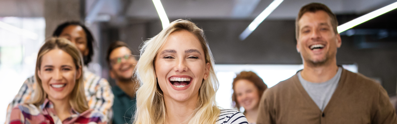 Gruppe lächelnder Menschen in einem modernen Büro, Freude und gute Stimmung.